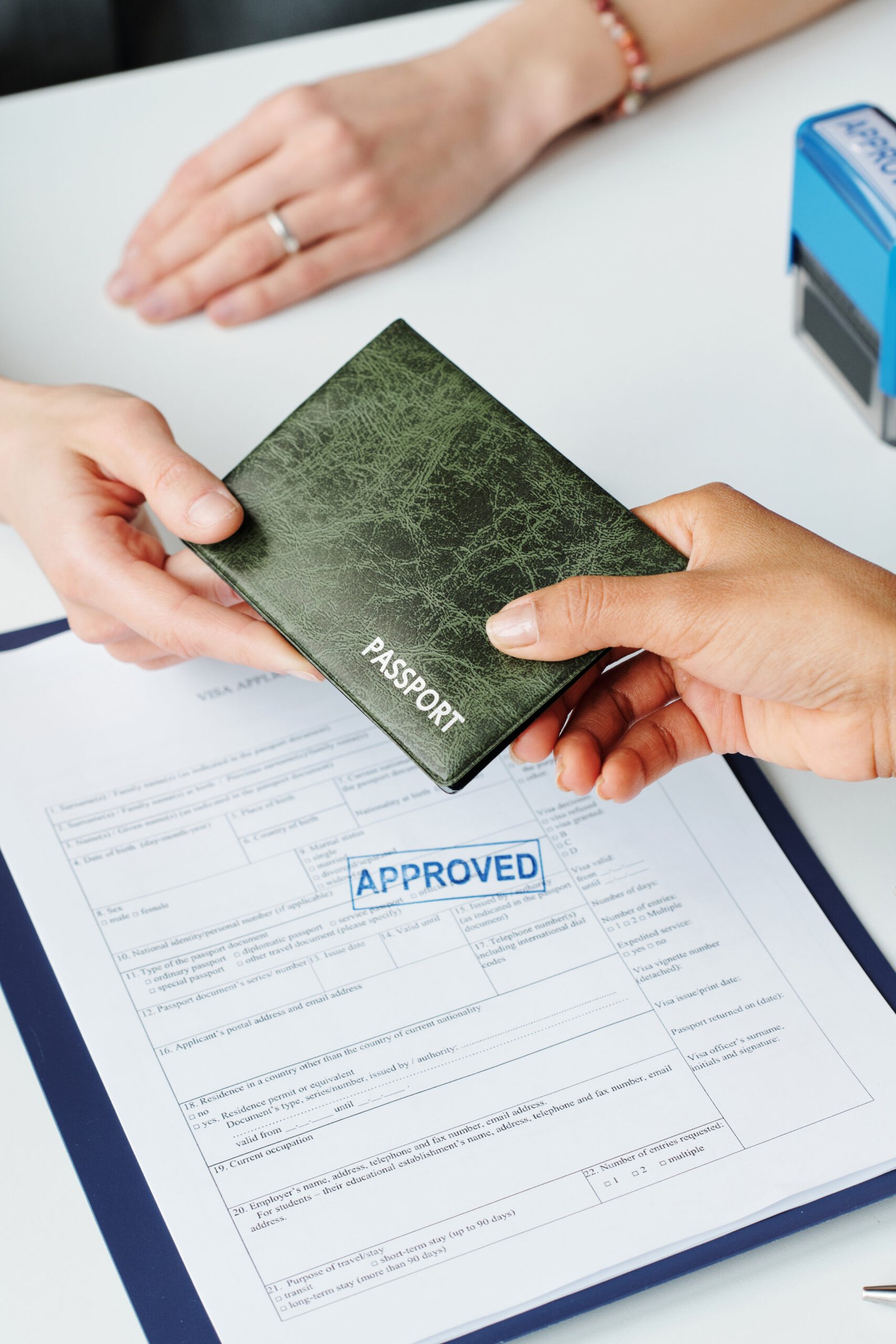 Vertical high angle of unrecognizable woman giving her passport to consular officer to make travel visa after successful application approval