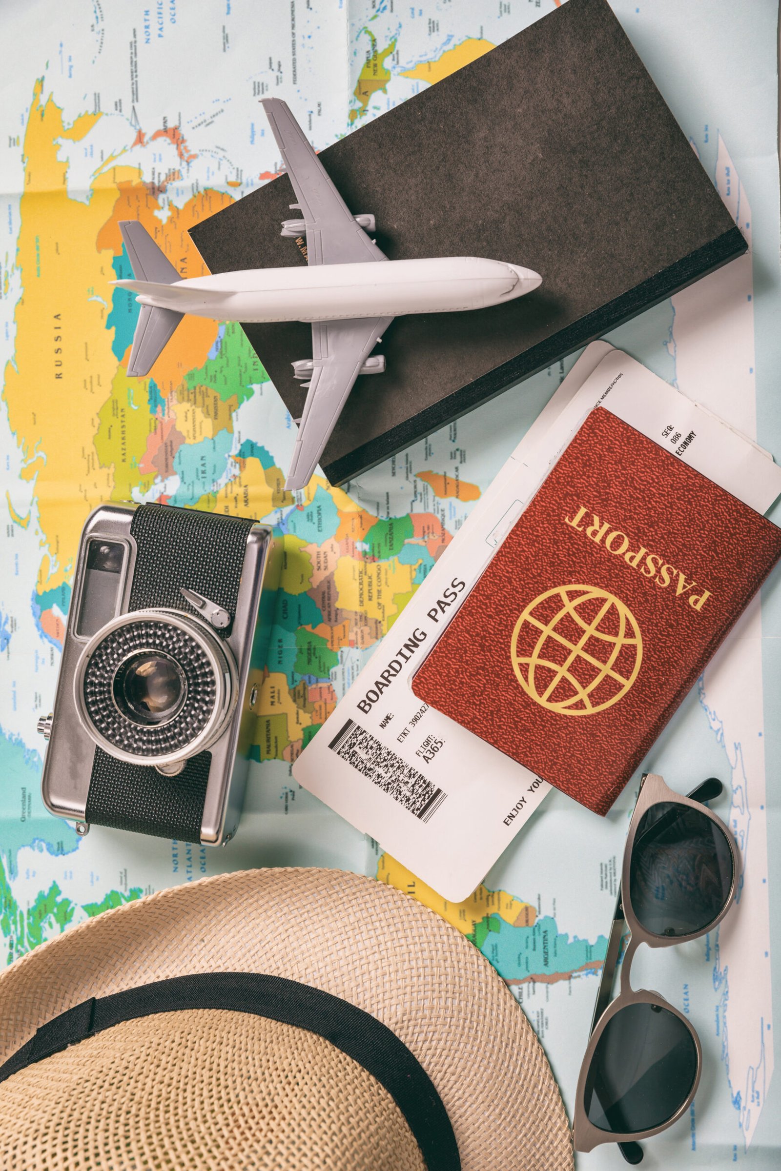 Travel and vacation accessories, map background. Voyage for tourism, business with essentials, tickets, passport, book, camera, eyeglasses, hat. Vertical, top view.