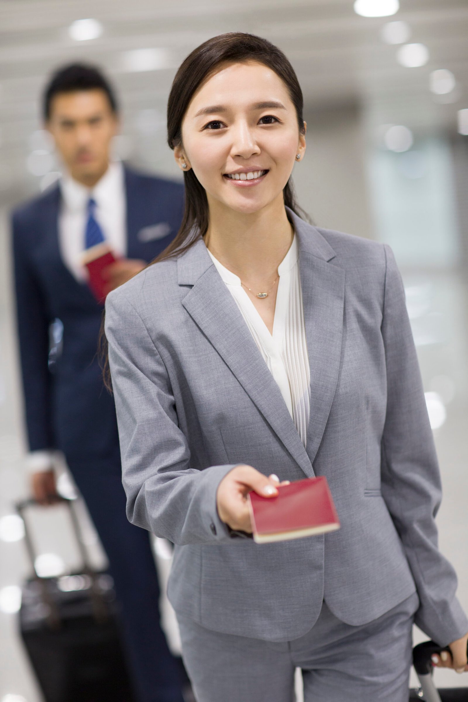 Young Chinese businesswoman showing her passport in airport